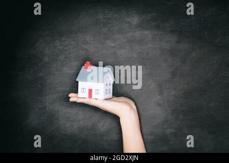 Immobilier fond de tableau noir - Nouvelle propriété de la maison femme montrant le jouet de maison miniature pour le concept d'affichage de propriétaire d'une maison. Banque D'Images