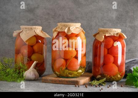 Tomates marinées maison. Légumes en conserve dans des pots en verre sur table grise. Banque D'Images