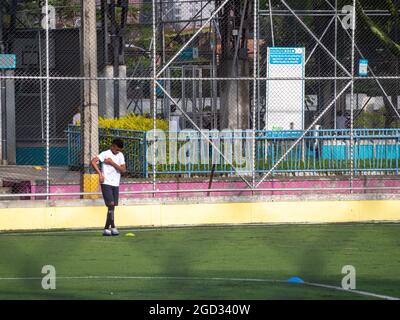 Medellin, Antioquia, Colombie - juillet 30 2021 : un jeune adolescent latin de Sportswear pratique Kicking a ball sur un champ d'herbe synthétique Banque D'Images