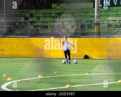 Medellin, Colombie - juillet 30 2021: Jeune adolescent latin est entraînement avec deux ballons de football sur un champ synthétique vert en une Journée de soleil Banque D'Images