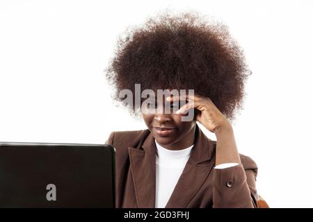 Jeune femme d'affaires noire hispanique Latina, avec des cheveux afro, avec un geste inquiet regardant son ordinateur portable, sur fond blanc Banque D'Images