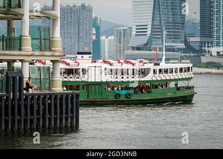 Le « Solar Star », l'une des flottes de Star Ferry, passe devant un homme pêchant à l'embarcadère Central Ferry Pier 8 sur l'île de Hong Kong tout en traversant le port de Victoria Banque D'Images