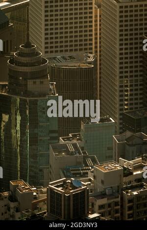 Immeubles résidentiels en hauteur à mi-niveaux et bâtiments commerciaux dans le centre de l'île de Hong Kong, rétroéclairés par le soleil tôt un matin brumeux Banque D'Images