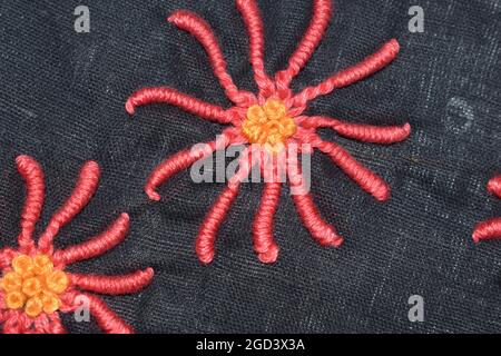 Fleur de pétales de couture booléenne au milieu du motif pancywork à noeud en français, broderie à la main cousue en douceur sur le tissu en popeline noir Banque D'Images