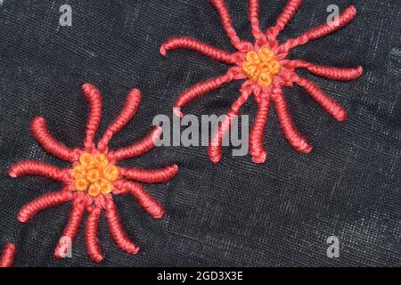 Fleur de pétales de couture booléenne au milieu du motif pancywork à noeud en français, broderie à la main cousue en douceur sur le tissu en popeline noir Banque D'Images