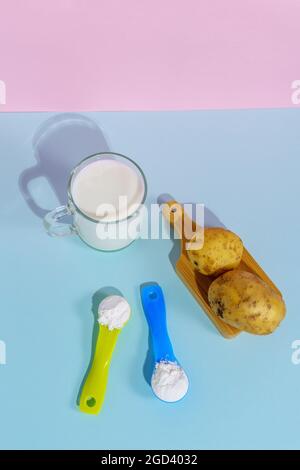 Lait de pomme de terre végétalien en poudre. Un verre de lait sur fond multicolore Banque D'Images