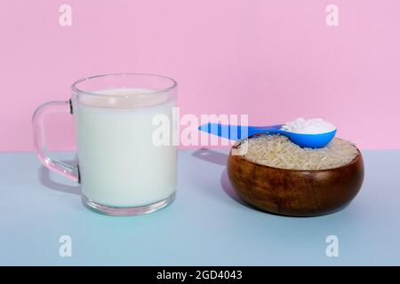 Lait de riz végétalien en poudre. Un verre de lait sur fond multicolore Banque D'Images