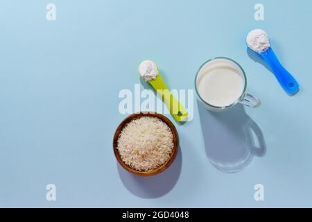 Lait de riz végétalien en poudre. Un verre de lait sur fond multicolore Banque D'Images