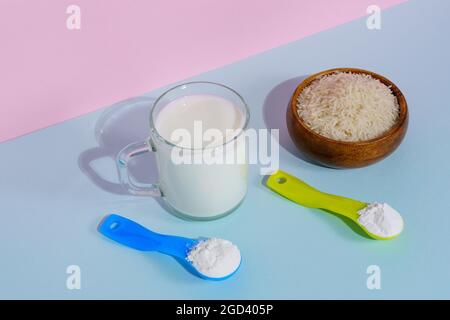 Lait de riz végétalien en poudre. Un verre de lait sur fond multicolore Banque D'Images