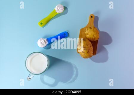 Lait de pomme de terre végétalien en poudre. Un verre de lait sur fond multicolore Banque D'Images