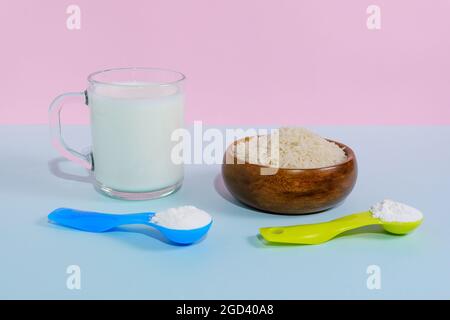 Lait de riz végétalien en poudre. Un verre de lait sur fond pastel multicolore Banque D'Images