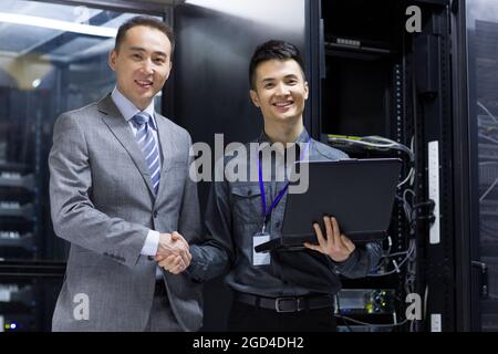 Les hommes d'affaires se secouent la main dans la salle informatique Banque D'Images