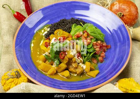 Curry de poulet aux lentilles noires et à la mangue sur une assiette bleue Banque D'Images