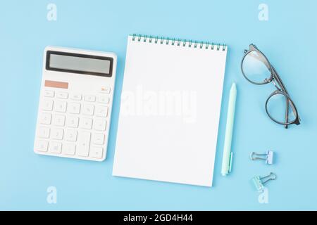 Bureau avec calculatrice, bloc-notes et lunettes. Banque D'Images