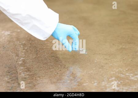 Un scientifique ganté prélève des échantillons d'eau dans un tube à essai à partir d'un lac fermé Banque D'Images