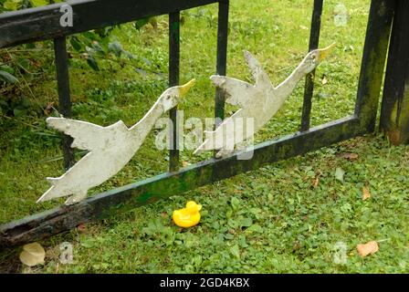 Petit canard en plastique jaune au sol à côté de la porte décoré de deux canards volants, Ludham, Norfolk, Angleterre Banque D'Images