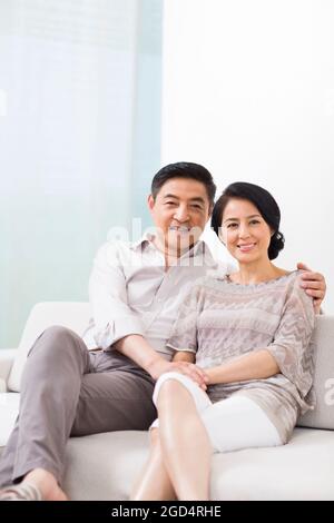 Heureux couple d'âge mûr assis sur un canapé à la maison Banque D'Images