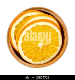 Tranches d'orange séchées, dans un bol en bois. Oranges, coupées en coupes transversales, fruits en tranches, utilisées comme décoration de Noël aromatique odorante. Banque D'Images