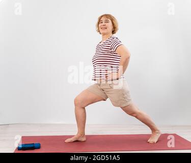 Femme âgée faisant des fentes sur fond blanc. Banque D'Images