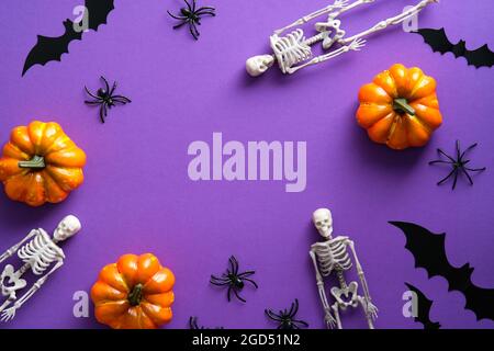 Cadre de décorations d'Halloween sur fond violet. Des squelettes plats, des silhouettes de chauves-souris, des araignées, des citrouilles. Joyeux Halloween concept. Banque D'Images