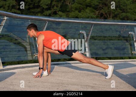 Sportsman tenir la position de fente faisant la routine d'étirement après l'entraînement sportif en extérieur, l'étirement Banque D'Images