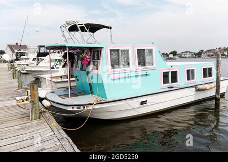 Babylone, New York, Etats-Unis - 29 juin 2019 : une péniche s'est emparée dans le décor électrique amarré à un quai peint avec des couleurs tropicales. Banque D'Images