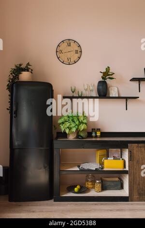 La cuisine est de style scandinave. Étagères en bois, décoration, réfrigérateur noir Banque D'Images
