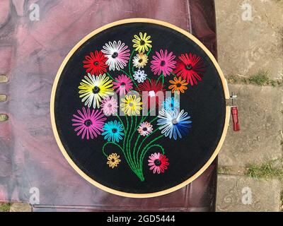 Broderie à la main décorations de fleurs, gros plan de la main embroider points de fleurs cousus avec des fils colorés sur le tissu en bois de broderie cadre Banque D'Images