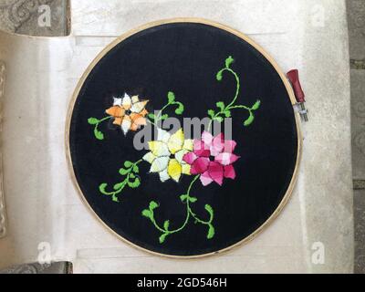 Broderie à la main décorations de fleurs, gros plan de la main embroider points de fleurs cousus avec des fils colorés sur le tissu en bois de broderie cadre Banque D'Images