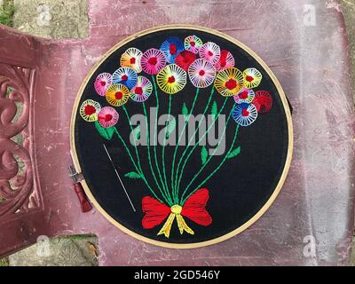 Broderie à la main décorations de fleurs, gros plan de la main embroider points de fleurs cousus avec des fils colorés sur le tissu en bois de broderie cadre Banque D'Images