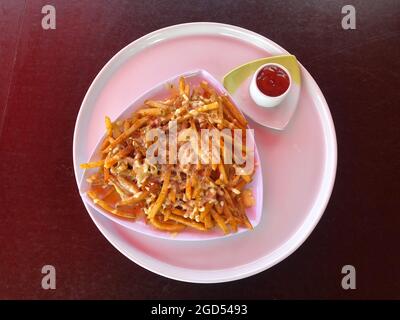 Vue rapprochée des frites avec sauce Chili, en-cas de pommes de terre frites, frites et coupe de tomate sur la plaque blanche Banque D'Images