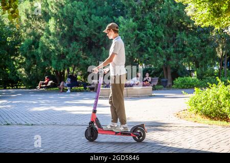 Un jeune homme conduit un scooter électrique loué dans le parc. Partage de scooter. Rostov-sur-le-Don, Russie, août 07 2021 Banque D'Images