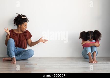 Violence domestique, maltraitance des enfants à la maison. Femme noire folle mère abusive gestante émotionnellement et criant à son enfant de pleurs, assis toge Banque D'Images