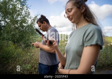 Jeune homme et femme regardant les écrans de leurs smartphones Banque D'Images