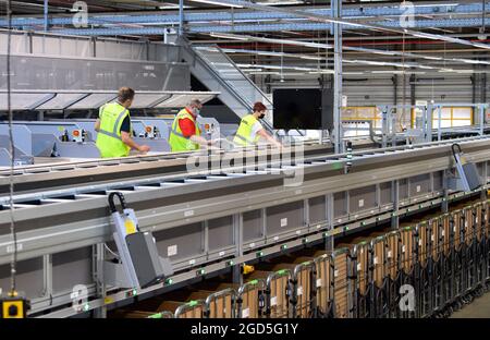 11 août 2021, Brandebourg, Stahnsdorf: Les employés travaillent sur le nouveau trieur multiformat au centre de courrier et de colis de Deutsche Post. Depuis 25 ans, Deutsche Post fournit des lettres aux clients de la grande région de Potsdam et des quartiers sud-ouest de Berlin via le centre. En attendant, de moins en moins de lettres sont envoyées, mais d'autant plus de colis et de petits colis. Le système trie également ces colis de petit format avec une épaisseur maximale de dix centimètres et un poids de 2,000 grammes, qui peuvent ensuite être livrés dans le réseau de courrier par le transporteur de lettres. Photo: Soeren Stache/ Banque D'Images