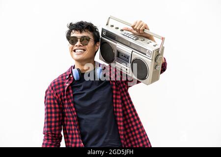 Jeune boxeur asiatique ayant de la musique amusante avec un casque et une boombox vintage pendant les vacances d'été Banque D'Images