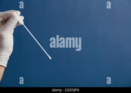 écouvillon buccal dans les mains du médecin ou de l'infirmière avec fond bleu Banque D'Images