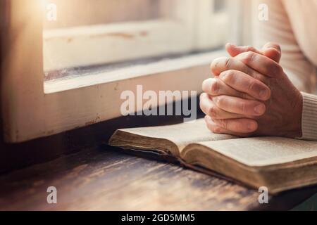 Mains d'une femme méconnaissable avec Bible priant Banque D'Images