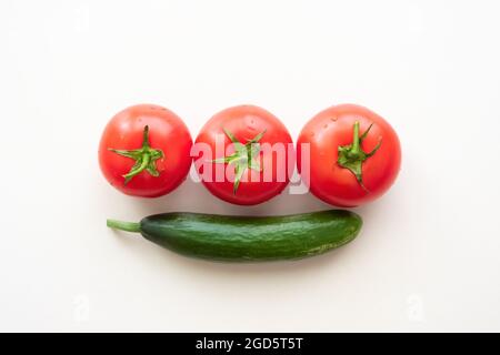 Trois tomates mûres et un concombre vert Banque D'Images