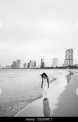 Charmante jeune femme asiatique en robe blanche marchant sur la plage. Photo romantique en noir et blanc. Photo de haute qualité Banque D'Images