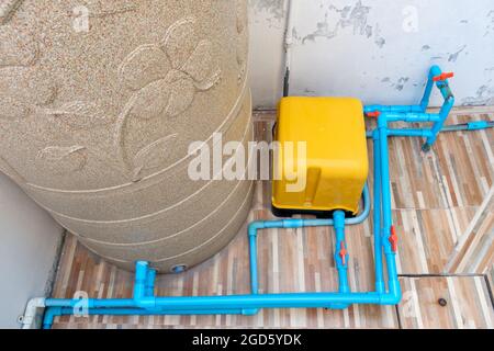 La pompe à eau automatique et le grand réservoir d'eau pour le système de distribution dans la petite maison de ville, près du coin du mur arrière, vue avant pour Banque D'Images