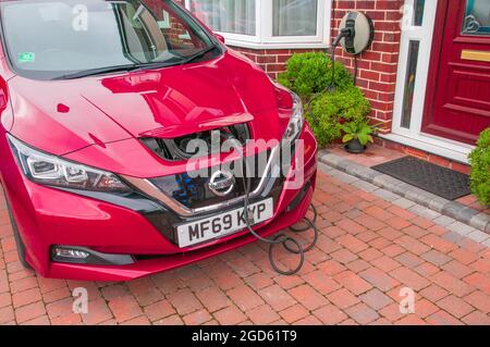 Charger une voiture électrique sur l'allée d'une maison mitoyenne au Royaume-Uni Banque D'Images