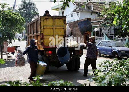 Bandung, Java-Ouest, Indonésie. 2 hommes transportent les déchets vers le camion à ordures Banque D'Images