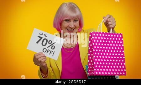 Femme granny âgée montrant des sacs de shopping et jusqu'à 70 pour cent de rabais sur les inscriptions texte, Black Friday Banque D'Images