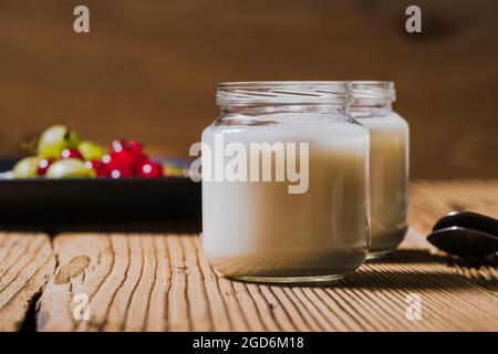 Smoothie petit-déjeuner, assiette avec groseilles à maquereau, raisins de Corinthe rouges, flocons d'avoine, deux bocaux avec kéfir sur table rustique en bois, gros plan, attention sélective Banque D'Images