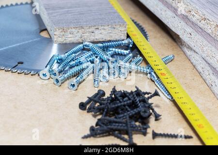 Les vis, les confirmations pour le mobilier, sont sur la table. Production de meubles Banque D'Images