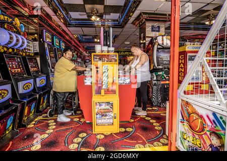 Les gens qui apprécient les arcades d'amusement jouant aux jeux de machines à sous à la station balnéaire de Paignton sur la côte sud du Devon, Angleterre, Royaume-Uni Banque D'Images