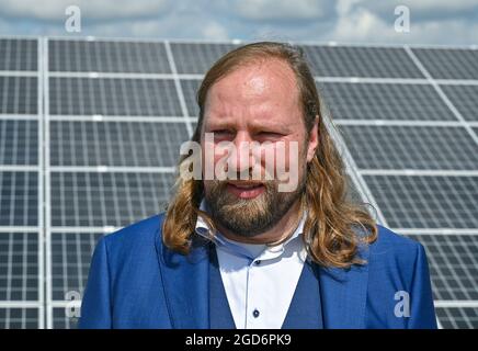 Werneuchen, Allemagne. 11 août 2021. Anton Hofreiter, chef de groupe parlementaire de Bündnis 90/Die Grünen, se dresse devant des modules photovoltaïques sur le site du parc solaire EnBW 'Weesow-Willmersdorf'. Anton Hofreiter a visité le parc solaire dans le cadre de sa tournée de l'industrie. Le parc solaire est le plus grand parc solaire d'Allemagne et, en même temps, le premier projet de photovoltaïque à grande échelle sans subventions EEG. La centrale a une capacité installée de 187 mégawatts. Credit: Patrick Pleul/dpa-Zentralbild/ZB/dpa/Alay Live News Banque D'Images