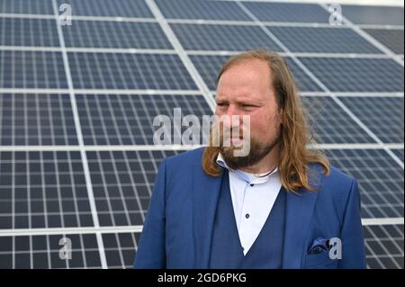 Werneuchen, Allemagne. 11 août 2021. Anton Hofreiter, chef de groupe parlementaire de Bündnis 90/Die Grünen, se dresse devant des modules photovoltaïques sur le site du parc solaire EnBW 'Weesow-Willmersdorf'. Anton Hofreiter a visité le parc solaire dans le cadre de sa tournée de l'industrie. Le parc solaire est le plus grand parc solaire d'Allemagne et, en même temps, le premier projet de photovoltaïque à grande échelle sans subventions EEG. La centrale a une capacité installée de 187 mégawatts. Credit: Patrick Pleul/dpa-Zentralbild/ZB/dpa/Alay Live News Banque D'Images