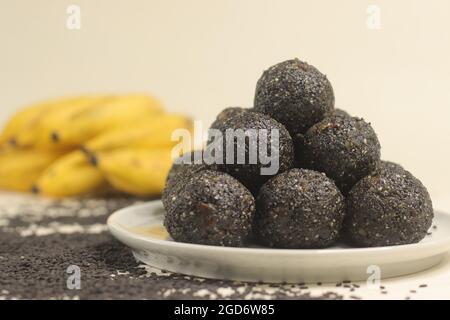 Des boules sucrées indiennes traditionnelles faites de graines de sésame, de jaggery et de noix de coco, communément appelées laddu de metil ke ou ladoos de sésame. Prendre avec la banane sur le dos Banque D'Images